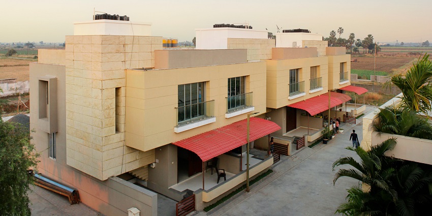 A breathtaking view of a hotel in Gujarat with yellow walls and lush trees in the day.