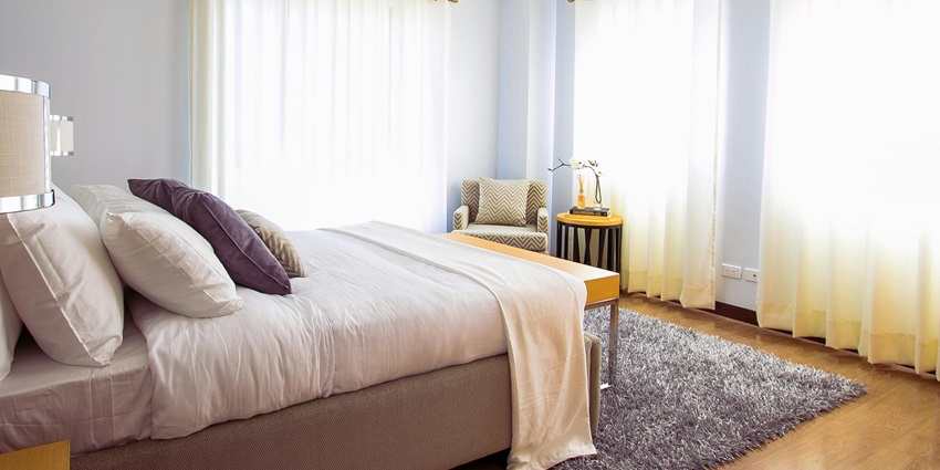A stunning view of a bedroom with a bed lined with white sheets and open curtains.
