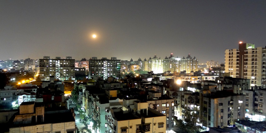 Surat at night, where city lights sparkle against a dark sky, with illuminated streets and buildings.