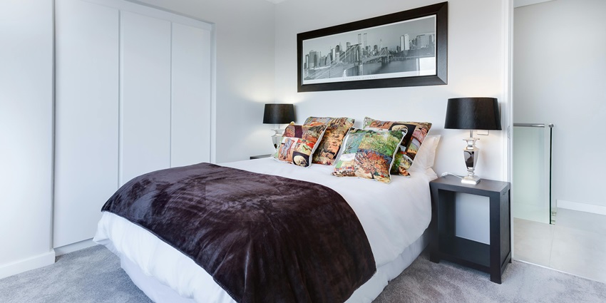 breathtaking view of a bedroom with a white bed and a side table during the daytime.