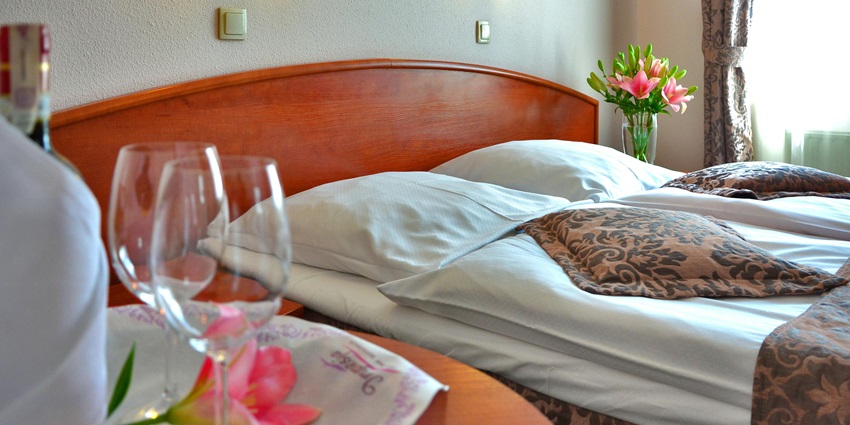 A breathtaking view of a bedroom with a side table with glasses on it and flowers.
