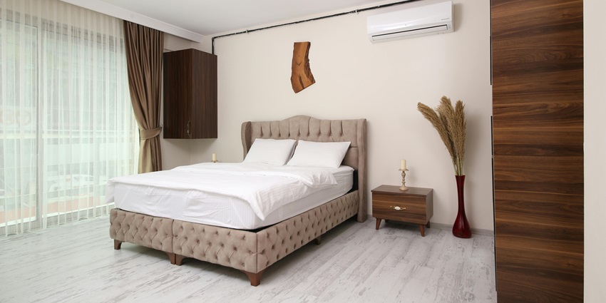 A fascinating view of a hotel room with a grey bed lined with white sheets and a table.