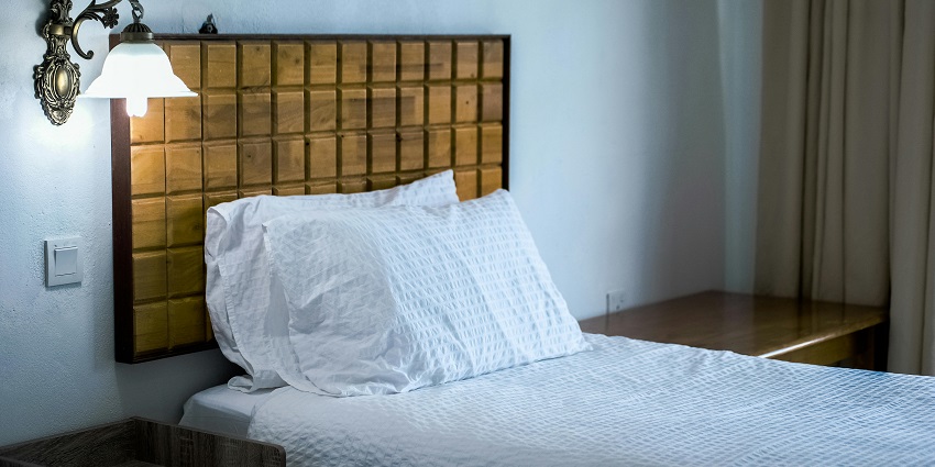 White bedding cover beside a brown wooden side table with a simple, clean aesthetic