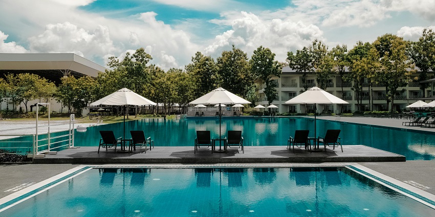 A black outdoor lounge chair positioned beside a blue swimming pool under a clear