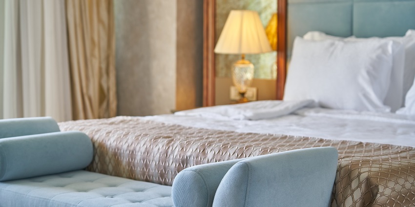An image showing a luxurious hotel bedroom featuring a large, elegantly designed bed