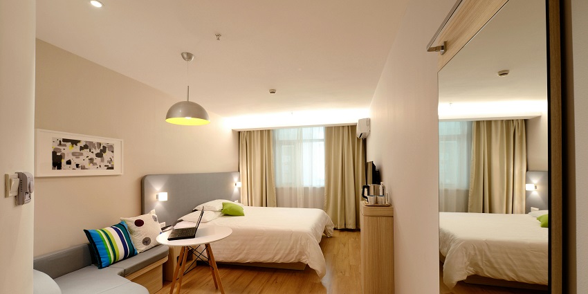 A hotel room with a neatly made bed, a comfortable seating area, and a window with a city view.