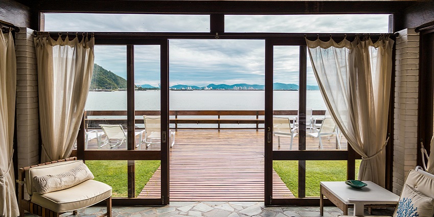 Image of a hotel room near the beach with a bed curtain and window beach view