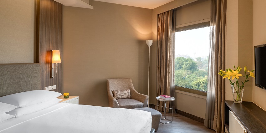 The inside of a bedroom in a hotel with sun light peeping through the windows.
