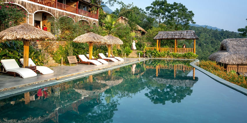 A picture of a resort with a swimming pool and beautiful pine trees in the background