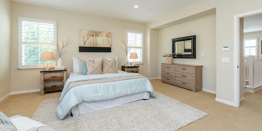 A stunning view of a bedroom with a bed lined with white sheets and grey pillows.
