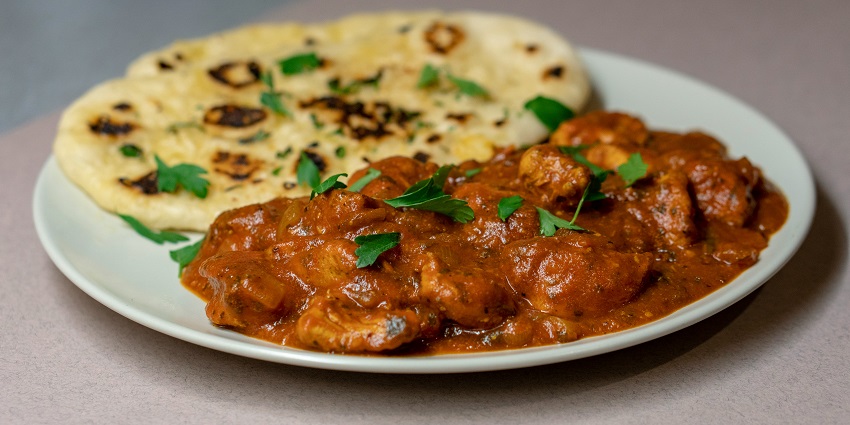 A mouth-watering view of a white plate served with a cooked dish and a flatbread.