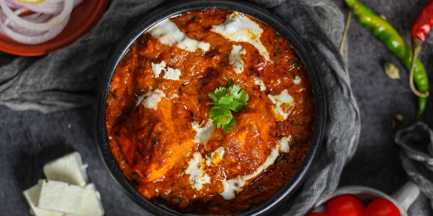 A mouth-watering aerial view of a cooked dish served in a black ceramic bowl on a table.