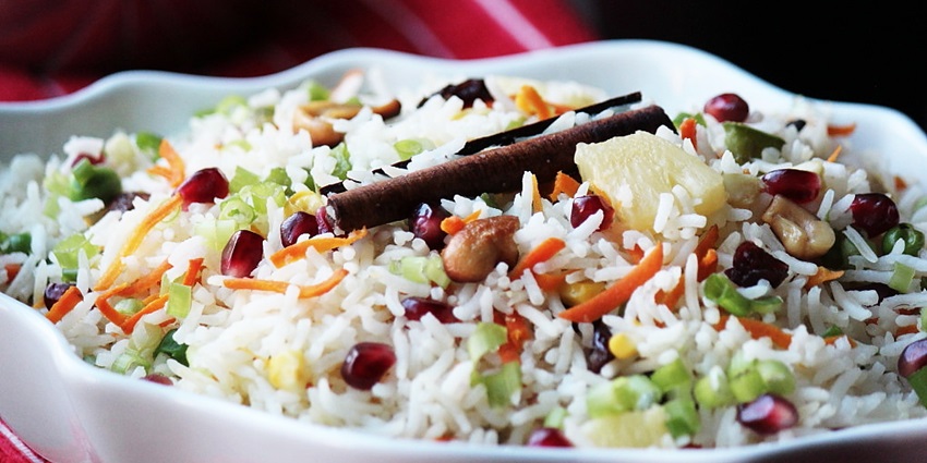 A bowl full of Kashmiri pulav with colourful vegetables and spices garnished on top.