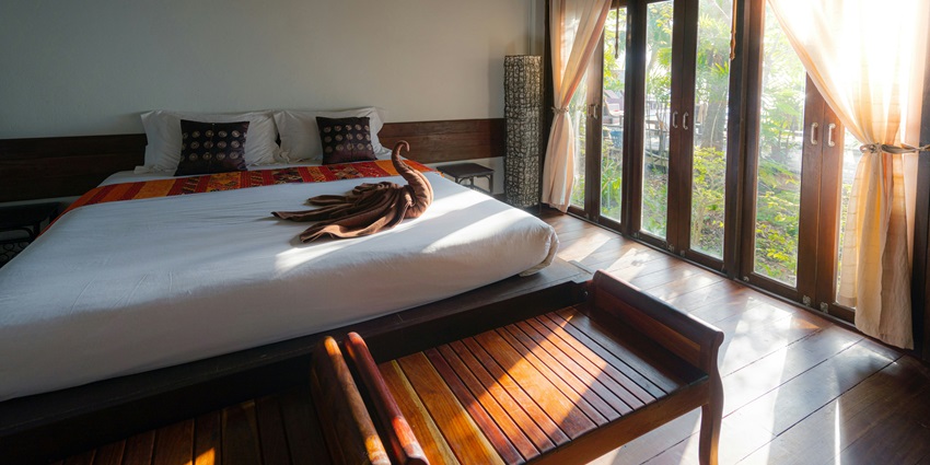 A stunning view of a bedroom with a bed lined with white sheets and a swan on it.