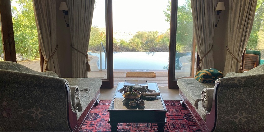A mesmerising view of a hotel room with an open window overlooking a water body.