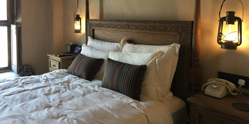 Pillows rest against a rustic wooden headboard in a cozy bedroom setting with a nice view.