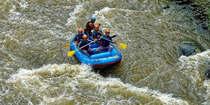 An image of five people performing the famous water sports rafting in an inflatable boat.