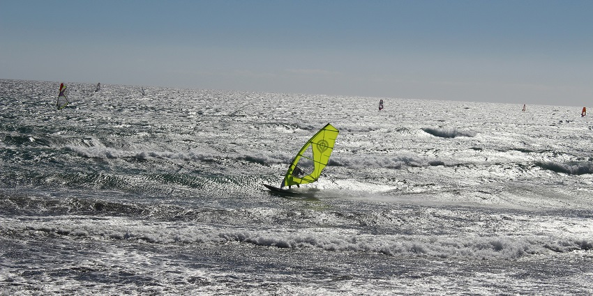 A person windsurfing on the glistening waves, one of the top Sinquerim Beach water sports.