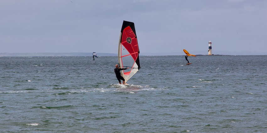 Image of people on windsurfing on clear blue beach water during day time