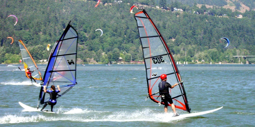 Windsurfers navigating the waters, surrounded by scenic hills and trees, another Calangute beach water sport to do.