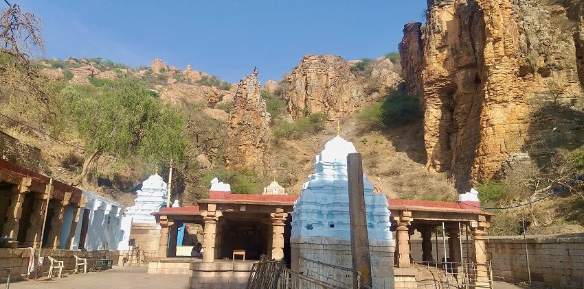 Distant view of halls of a temple in Yaganti with rocky mountains in the background