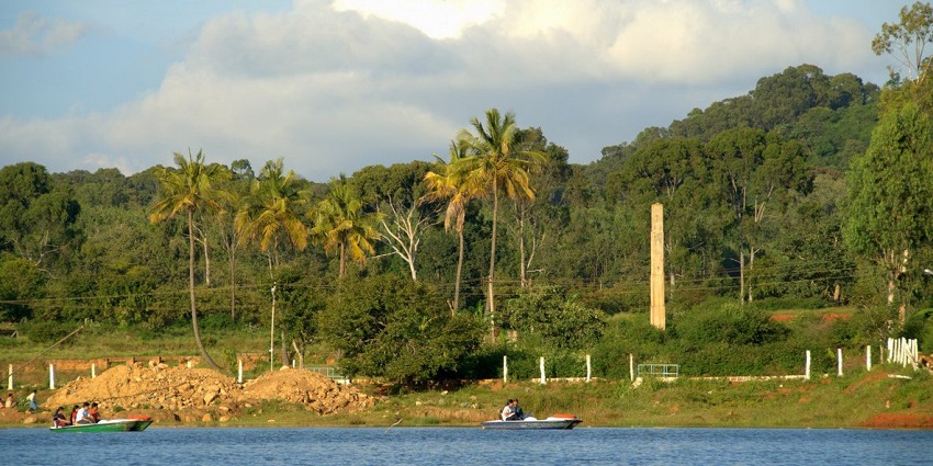 Serene sight of the Yelagiri lake, boats sailing and lush vegetation on the shores with tall palms