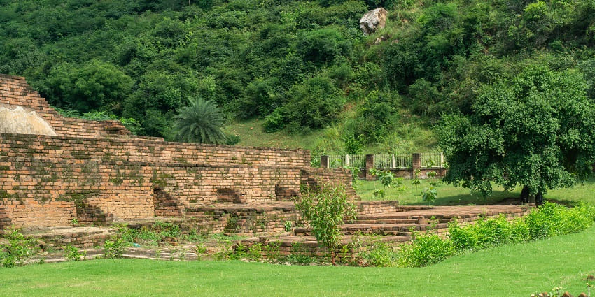 A picture of a lush green region near the Ajatshatru Fort with walls of a ruined historical building