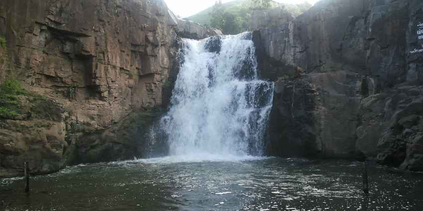 Picturesque view of Zarwani Waterfall in the lush greenery water caseding through the big ricks
