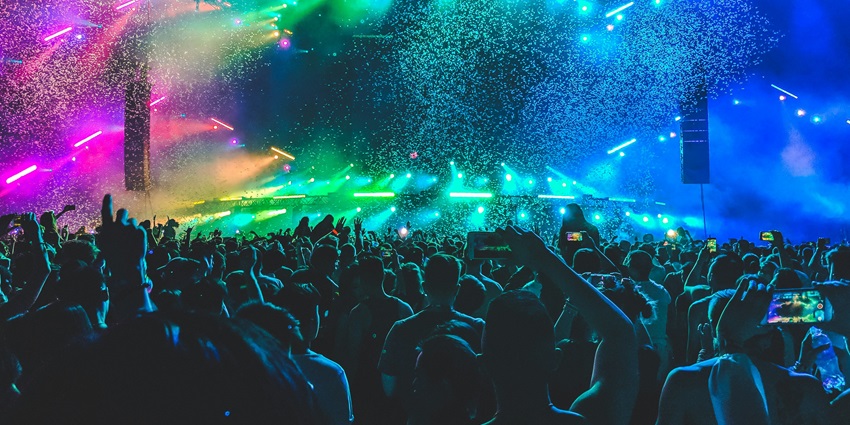 A glimpse of people enjoying and dancing in a club adorned with colourful neon lights.
