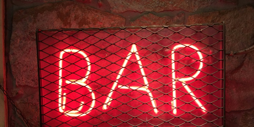 A lively bar with bright LED signage, creating an inviting ambiance filled with colorful lights