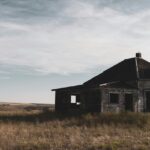 A glimpse of an abandoned house sitting on a sprawling barren land exuding vintage vibes.