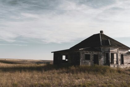 A glimpse of an abandoned house sitting on a sprawling barren land exuding vintage vibes.