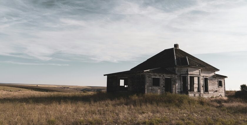 A glimpse of an abandoned house sitting on a sprawling barren land exuding vintage vibes.