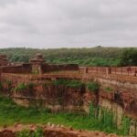 A view of the Ranthambore Fort, perched on a hilltop and surrounded by dense greenery.