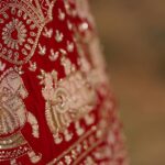 A glimpse of a bright red coloured bridal attire adorned with golden embroidery.