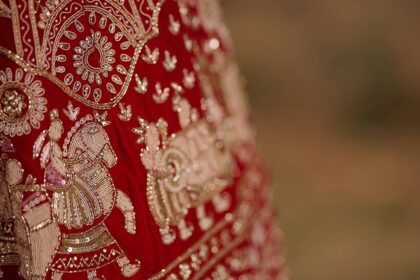 A glimpse of a bright red coloured bridal attire adorned with golden embroidery.