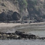 A breathtaking view of a beach in Alibaug with small and big rocks during the daytime.