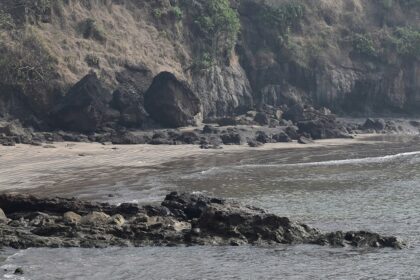 A breathtaking view of a beach in Alibaug with small and big rocks during the daytime.