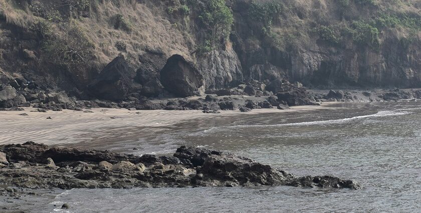 A breathtaking view of a beach in Alibaug with small and big rocks during the daytime.