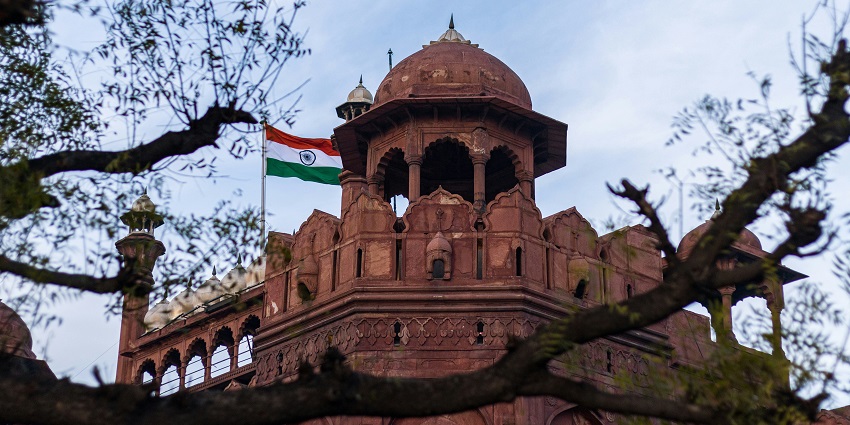 A breathtaking view of the red fort with stunning architecture around lush trees.