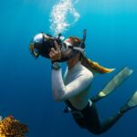 A breathtaking view of a woman enjoying an underwater activity surrounded by corals.