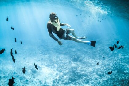 A glimpse of a person diving deep in the azure ocean exploring the marine life underwater.