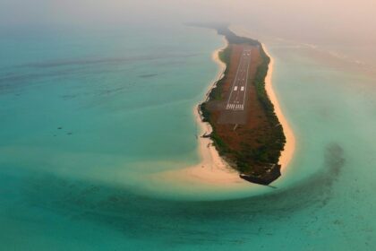 A breathtaking view of a lush green island surrounded by turquoise waters on all sides.