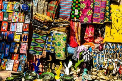 Colourful handicrafts, bags, ceramic plates, and earrings being sold in a market.