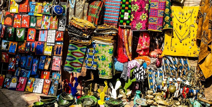 Colourful handicrafts, bags, ceramic plates, and earrings being sold in a market.