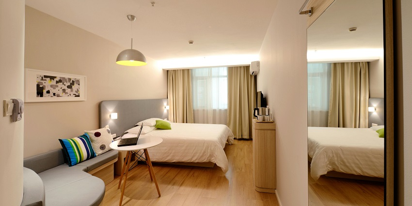 A breathtaking view of a bedroom with a bed lined with white sheets and colourful pillow.