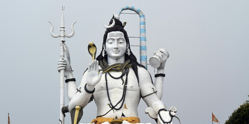 A picture of a tall Shiva statue taken on a sunny day