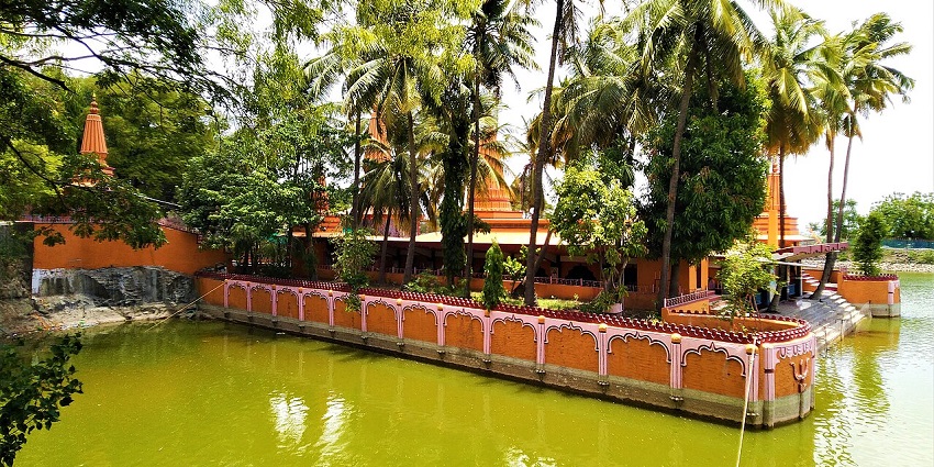 A scenic view of Ramdara Temple by the lake, surrounded by lush greenery and tranquility.