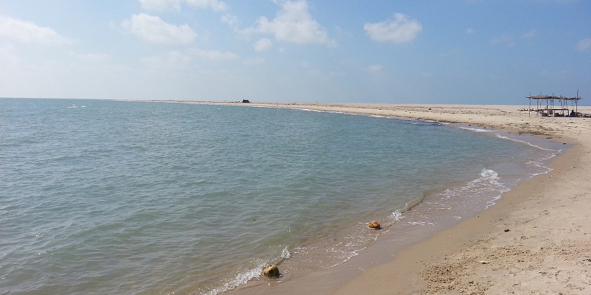 A picture of a scenic beach with a naturally occurring bridge connecting two landmasses