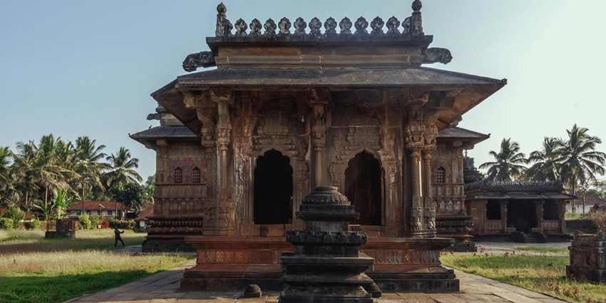 An old Hindu temple in Tamil Nadu with intricately carved stone pillars and ornate sculptures.